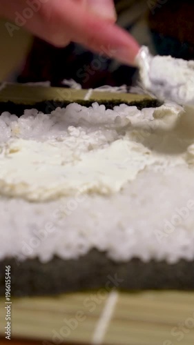 Sushi making spreading fresh cheese on nori with rice using spoon for homemade sushi roll vertical