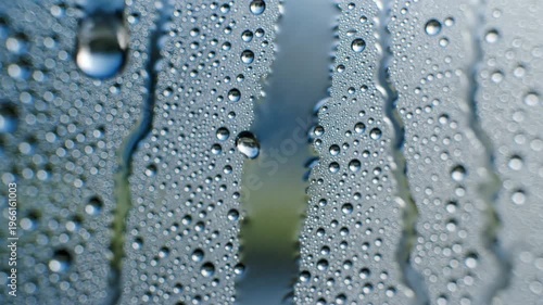 Condensation on glass creates a hazy, atmospheric texture of soft light streaks and blurred droplets, evoking humidity and refreshing coolness in an abstract close-up.