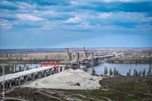 Large-scale construction of a modern cable-stayed bridge with tall tower cranes over a wide river