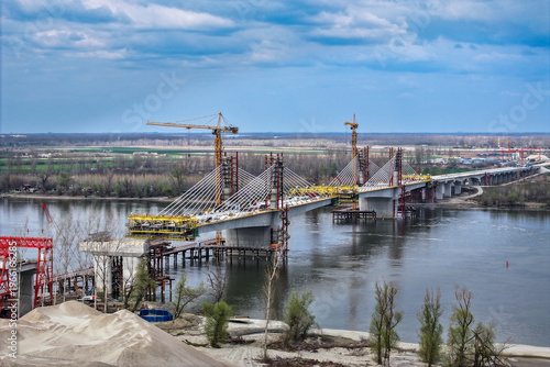 Large-scale construction of a modern cable-stayed bridge with tall tower cranes over a wide river
