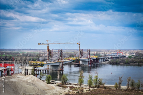 Large-scale construction of a modern cable-stayed bridge with tall tower cranes over a wide river