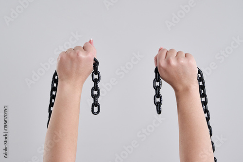 Tableau sur toile Female hands holding a broken metal chain over grey background with copy space