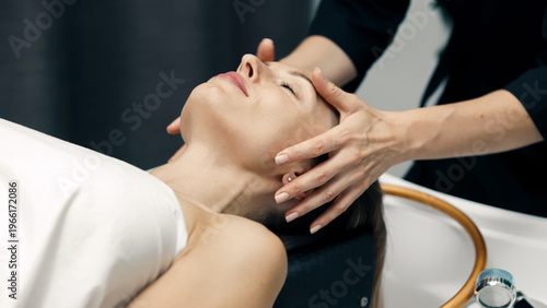 Woman receiving relaxing face massage in beauty salon. Close up wellness and self care concept.
