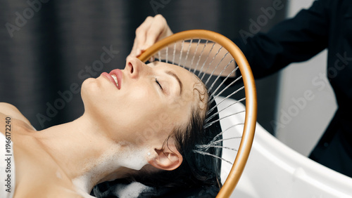 Japanese head spa treatment for relaxation, gentle water flow massaging young woman’s scalp.
