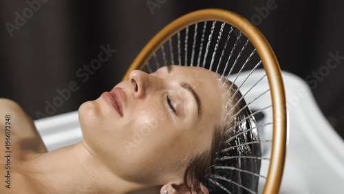Woman undergoing Japanese spa treatment with circular water massage, deep relaxation concept.
