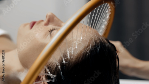 Japanese head spa therapy with gentle water stream, woman enjoying stress relief and relaxation.
