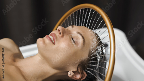 Close up of young woman enjoying head spa massage with flowing water. Beauty and anti-stress therapy.

