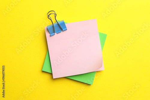 Reminder. Sticky notes with binder clip on yellow background, top view