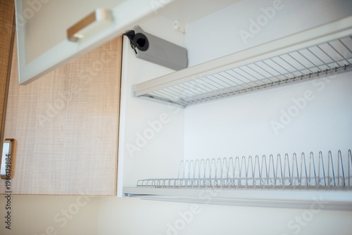 Open kitchen cabinet with wire rack and wooden shelves visible inside