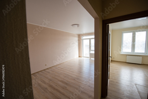Empty modern apartment interior with large windows and wooden flooring