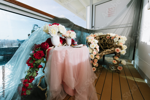 Floral arrangement on table with draped fabric on balcony overlooking water