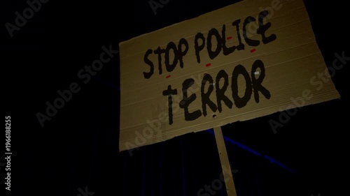Close-up of protester holding cardboard sign reading “Stop police terror” during street demonstration. Civil rights activism, public protest, anti-violence rally, social justice, human rights awarenes