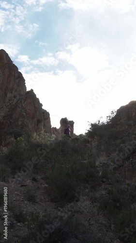 Silhouetted person hiking through a narrow and rocky mountain pass in nature