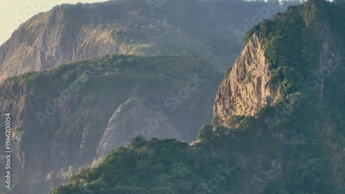 A scenic view of the cliffs and ocean in Karekare, Auckland, New Zealandl. The cliffs are covered in lush vegetation, and the ocean is a beautiful blue color.