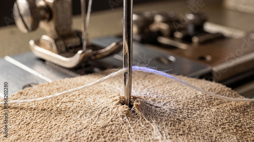 Extreme macro of a needle stitching through porous mycelium leather, featuring laser-guided precision in the manufacturing of sustainable bio-engineered textiles