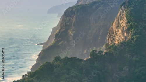 A scenic view of the cliffs and ocean in Karekare, Auckland, New Zealandl. The cliffs are covered in lush vegetation, and the ocean is a beautiful blue color.