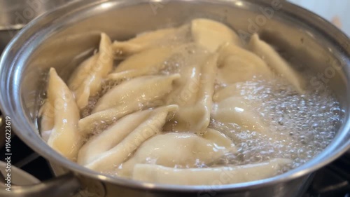 Close-up of pierogies boiling in a pot of water on the stove. Traditional comfort food cooking with bubbling water and dumplings rising to the surface. 15107  