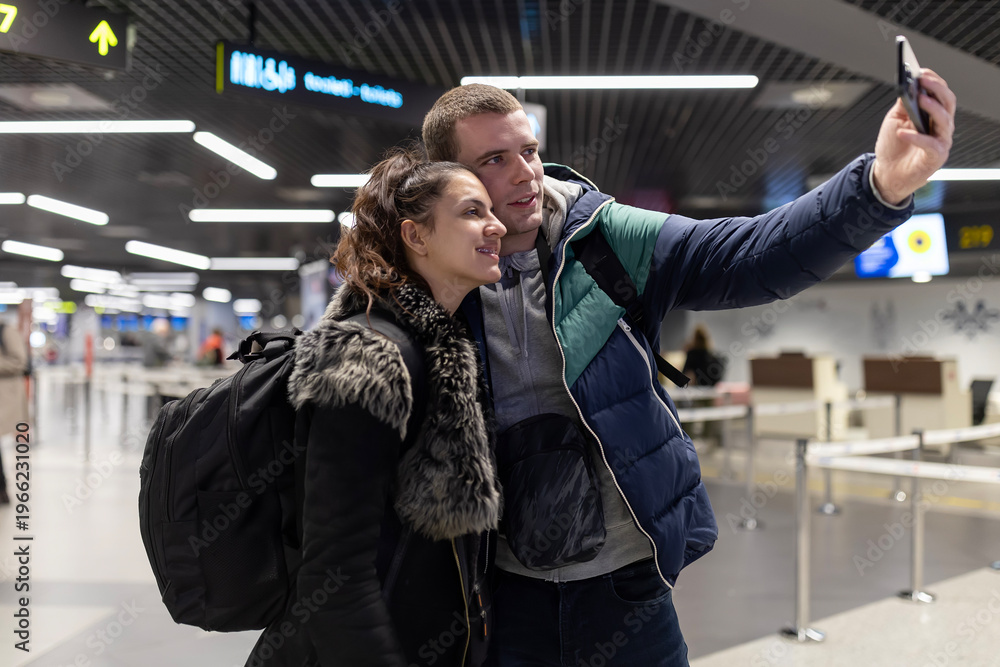 Fototapeta premium Young couple taking travel selfie at airport