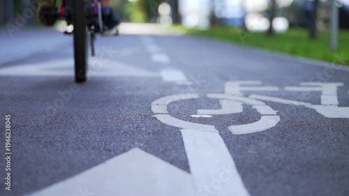 A young boy practices cycling in a public park. Camera captures only wheels and small legs. The ride is unstable and careful. Concept of learning balance, childhood development and outdoor training.