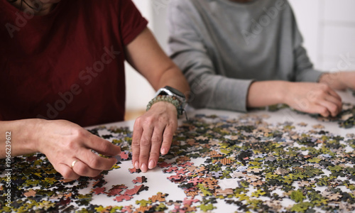 Family Spends Time Together As Female Hands Assemble A Puzzle On A Table