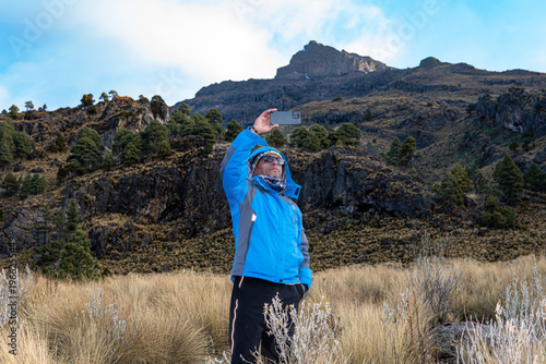 Hiker documenting iztaccihuatl volcano with smartphone in mexico