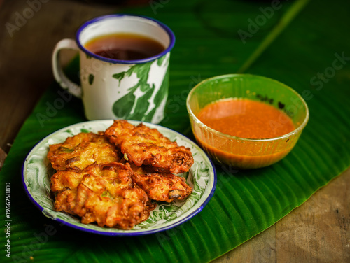 Wallpaper Mural A plate of bakwan sayur, Indonesian vegetable fritters, served with a dipping sauce and a cup of tea on a green leaf in Indonesia. Torontodigital.ca