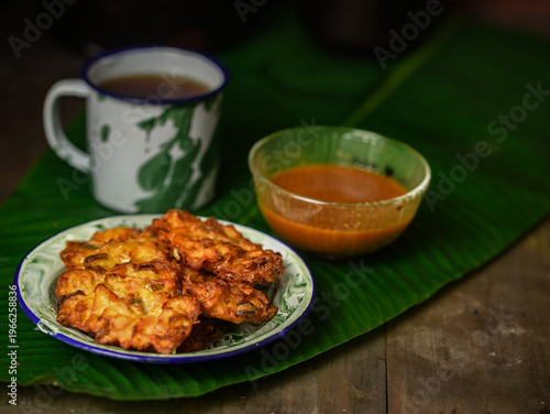 Wallpaper Mural A plate of bakwan sayur, a traditional Indonesian vegetable fritter, served with a dipping sauce and a cup of coffee on a banana leaf in Indonesia. Torontodigital.ca