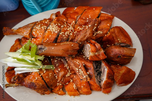 Wallpaper Mural Roasted duck dish served on a white plate with sesame seeds and green onions, set on a wooden table in Indonesia. Torontodigital.ca