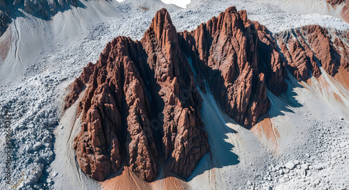 Aerial view of rugged red rock mountain peaks surrounded by grey scree slopes and rocky terrain