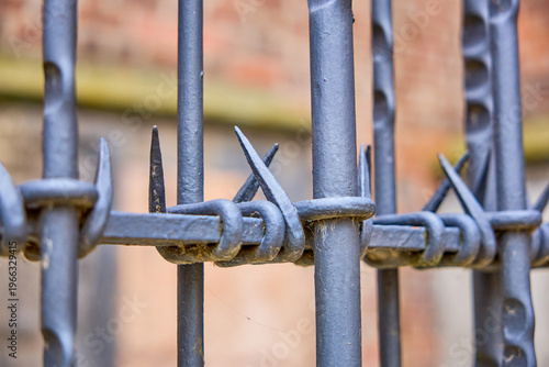 фотографія Close-up of barbed wire on metal fence against brick wall background