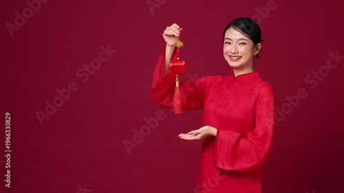 Asian woman raising fist in excitement, red festive clothing, energetic mood for New Year celebration campaigns.