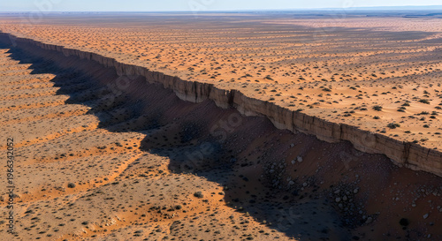 Aerial view of a long, straight escarpment cutting through a vast, arid desert landscape with sparse vegetation