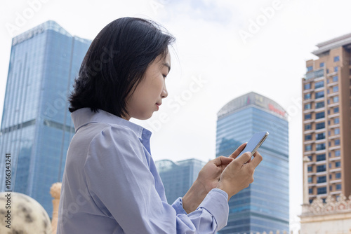 Free Download A portrait of an Eastern businesswoman, an urban white-collar worker, using her mobile phone - GFXLoad