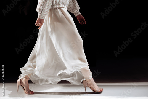 Fotografie Chic satin long white skirt and beige high heels, woman's elegant outfit on blac