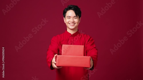 Asian man offering gift box forward, red festive background, New Year promotion concept. Advertising video for New year concept