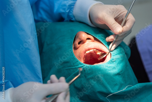 Fotografi Dentist examining patient teeth with mirror and tools under sterile drape focusi