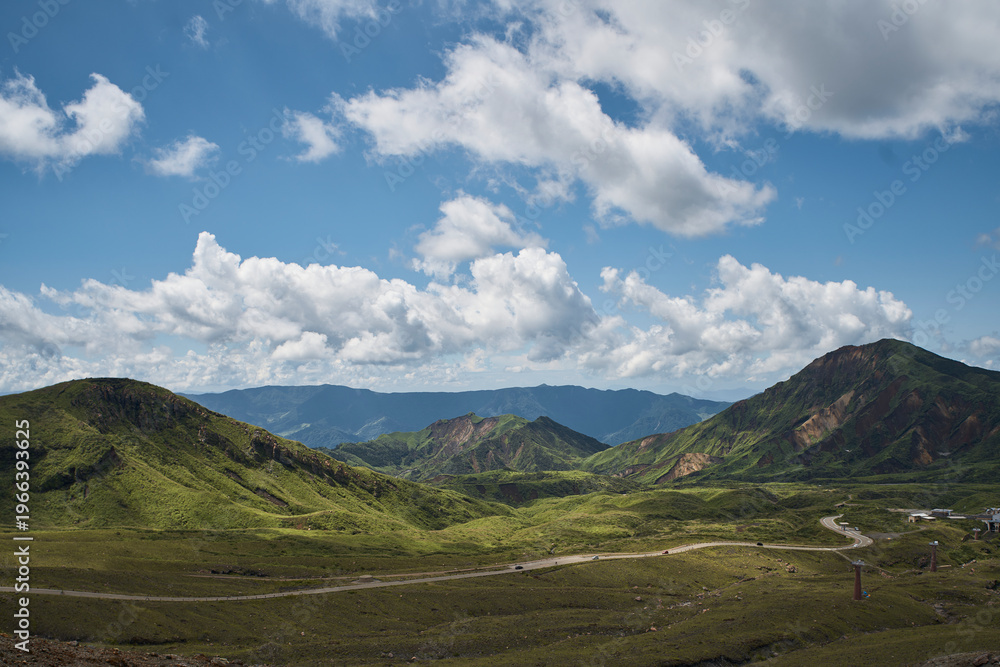 Fototapeta premium Vast volcanic landscape with green mountains, crater terrain and dramatic summer clouds