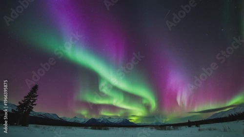 a stunning and dramatic view of the Aurora Borealis (Northern Lights) over the snowy mountains.