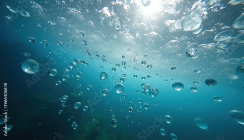 Underwater view of shimmering air bubbles rising towards the sunlit ocean surface creating a dynamic abstract pattern