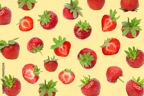 Strawberries of various sizes placed on a yellow surface