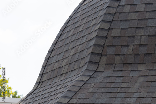 roof shingle background and texture. dark asphalt tiles on the edge of curve roof.
