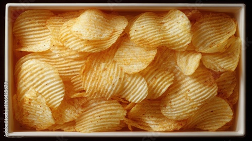 Crispy Golden Potato Chips in a Rectangular Container on Black Surface