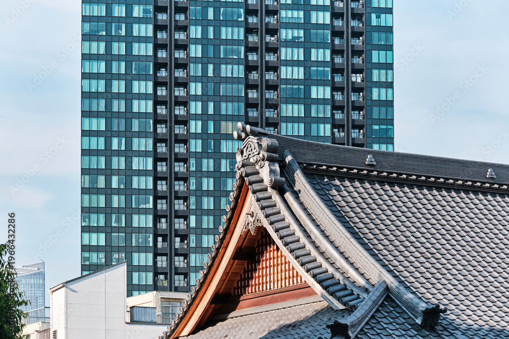 Naklejka premium Traditional tiled roof with modern glass tower rising behind in urban contrast