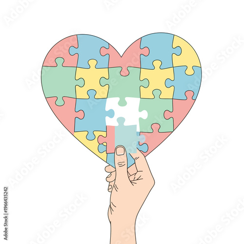 Hand placing last puzzle piece into colorful heart shape, autism awareness symbol