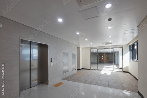 Clean elevator lobby with gray floor and bright end window in modern building