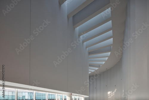 Curved white corridor with skylight slats in contemporary building interior
