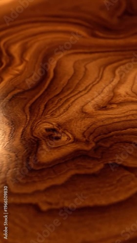 Close-up view of the rich, swirling grain pattern on a polished wooden surface with warm lighting highlighting the texture
