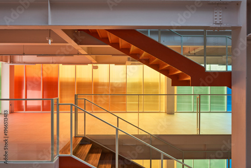 Colorful atrium with translucent walls and orange stair in modern building