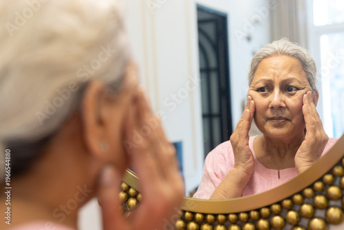Senior indian woman touching face check facial wrinkles looking in mirror reflection, Old mature 60s female concern about her face skin. Aging process.