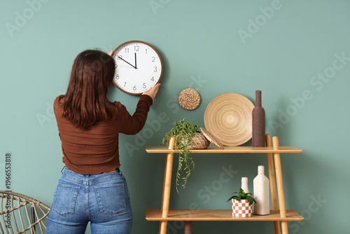 Young woman hanging clock o...